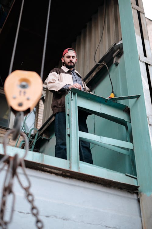 Man Standing by a Metal Industrial Lift