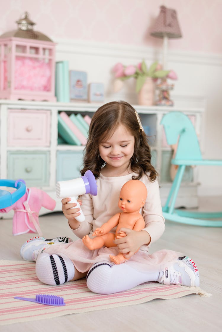 Little Girl Playing With Doll In Room