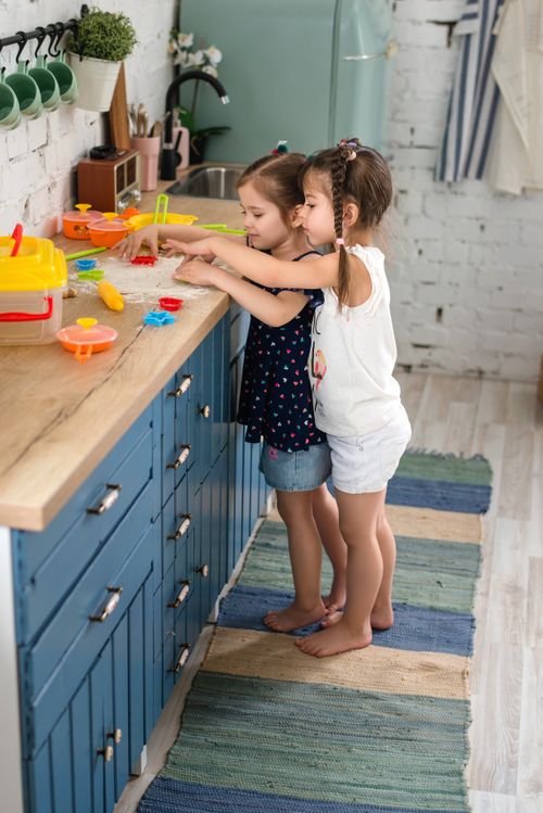 Free Two young girls enjoying playful activities on a kitchen countertop, engaging with toys. Stock Photo