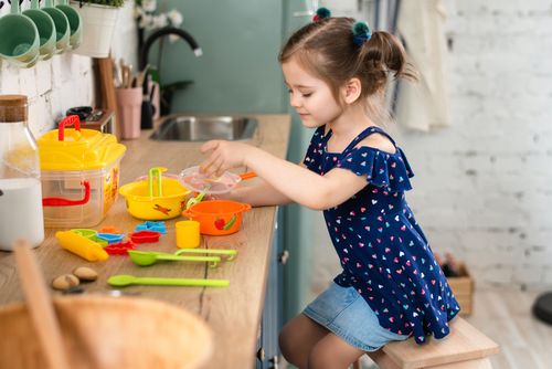 Free Young girl engaged in imaginative play with kitchen toys on a countertop. Stock Photo