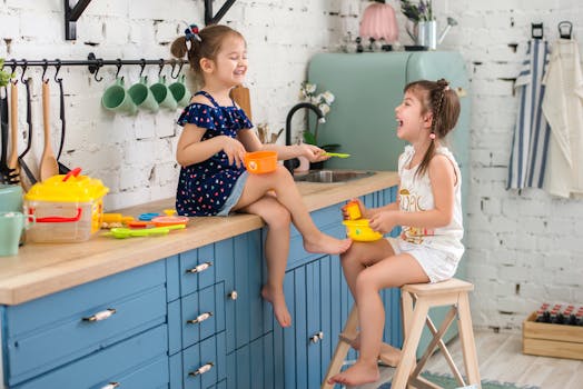 Two young girls enjoying imaginative play with plastic toys in a cozy kitchen.