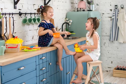 Free Two young girls enjoying imaginative play with plastic toys in a cozy kitchen. Stock Photo