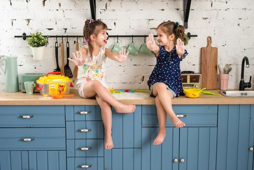 Free Two smiling girls playing with toys on a kitchen counter in a cheerful indoor setting. Stock Photo