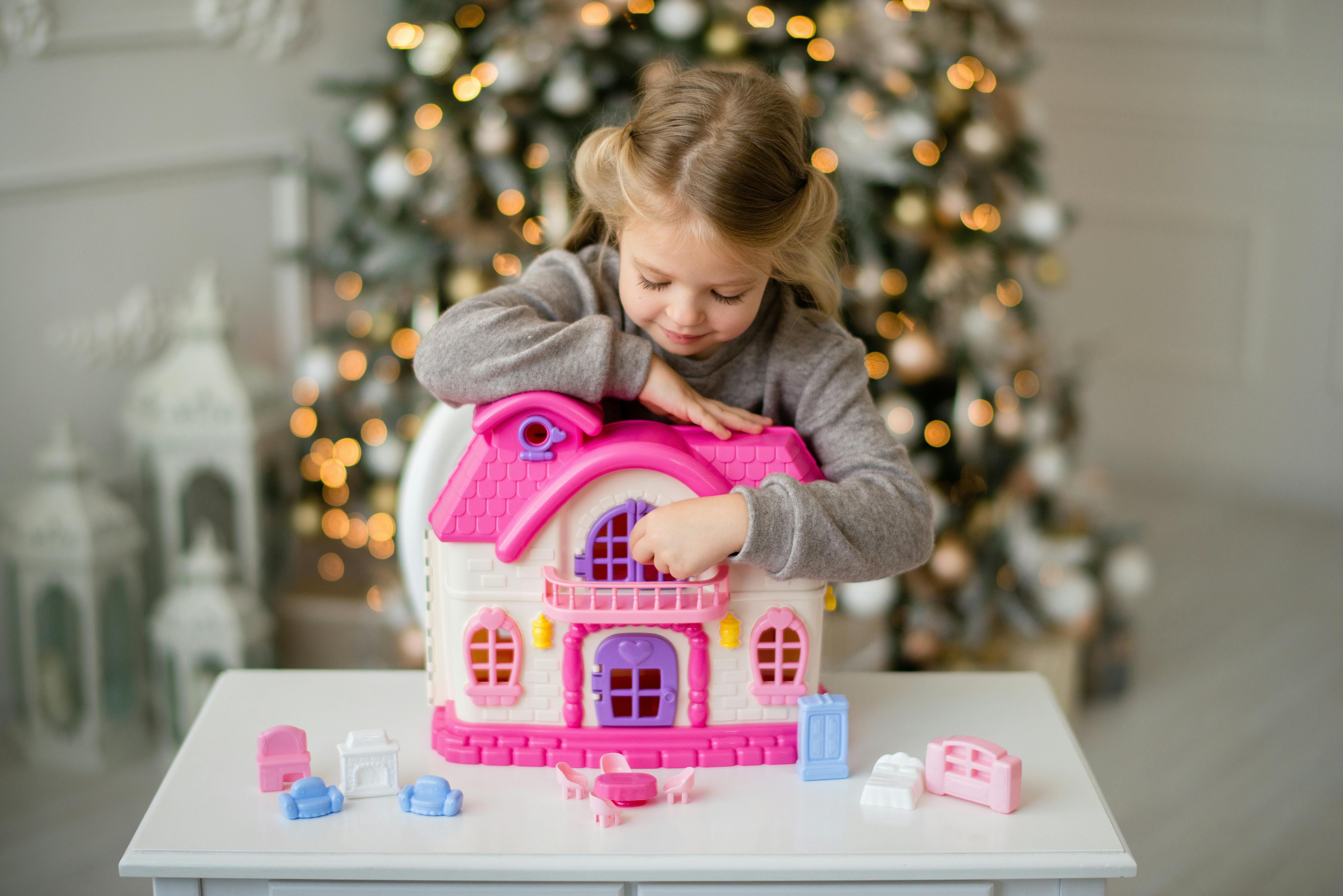 girl in gray sweater playing with a doll house