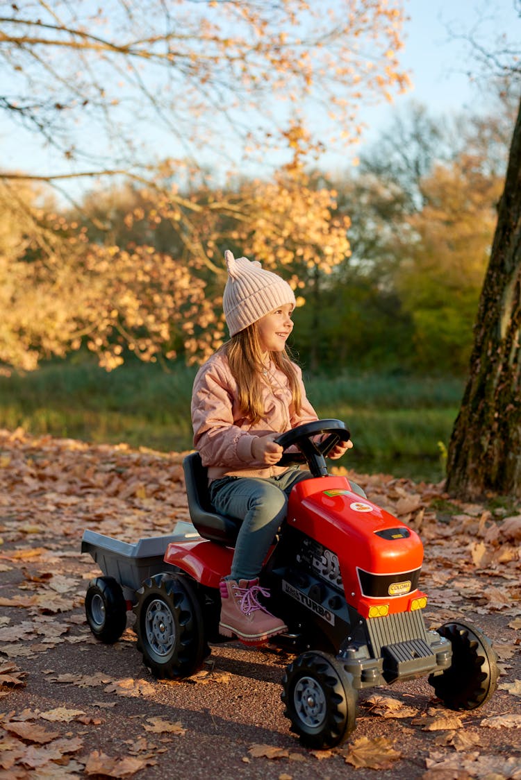 A Little Girl Riding A Tractor Toy