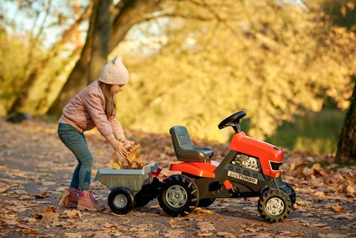 Free Girl Putting Leaves on a Toy Tractor Stock Photo