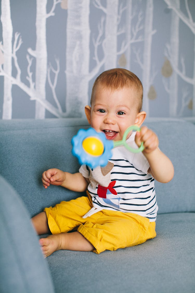 A Child Holding A Rattle Plastic Toy