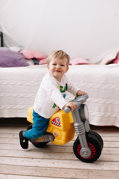 A Child Riding on His Plastic Toy 
 Motorbike 