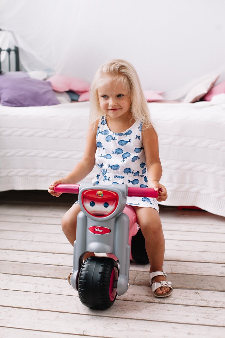 A Cute Girl Riding On Her Plastic Toy Motorbike