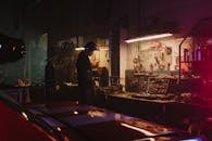 在灯光昏暗的车库车间里，机械师在工具和设备的环绕下工作