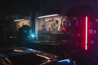 在光线昏暗的车库里，机械师在霓虹灯和工具的环绕下工作