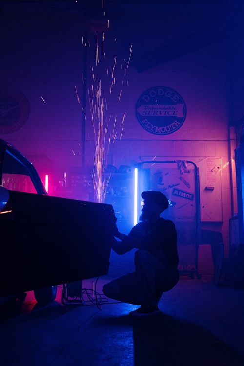 Free Silhouetted mechanic welding in a neon-lit garage, creating dramatic sparks and shadows. Stock Photo