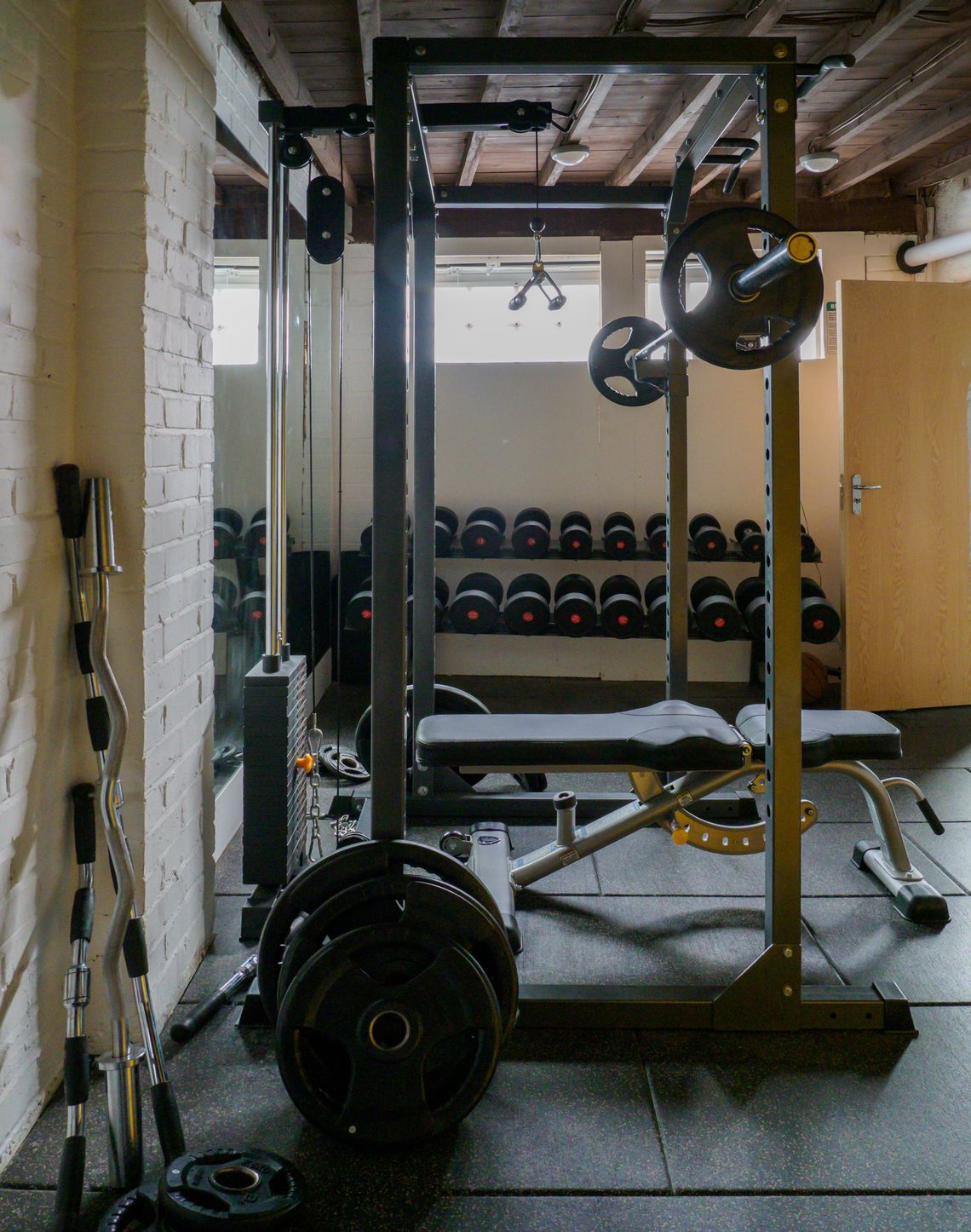 Real compact home gym with weight bench, dumbbells, weight plates, and strength equipment