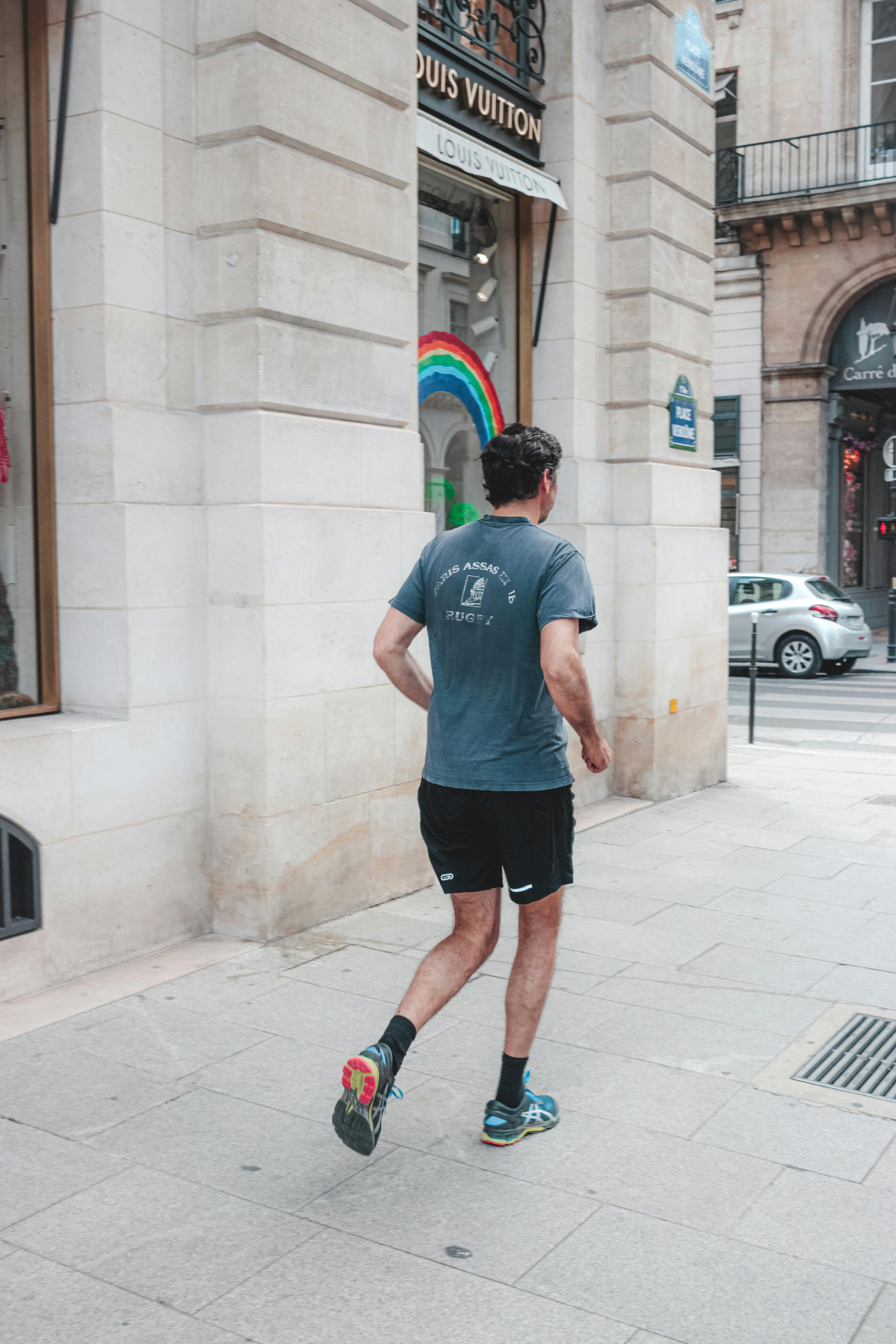 faceless male jogger running along paved street sidewalk