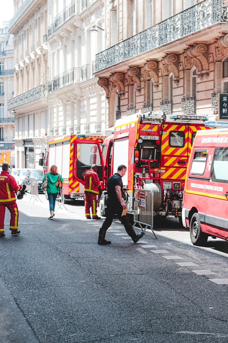 Firefighters Walking Near Fire Engine And Ambulance On City Road