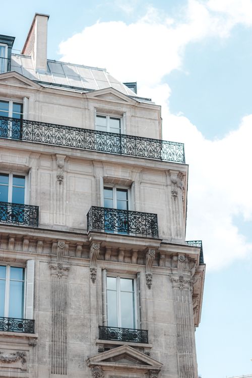 Free Low angle corner of historic old building with small decorative balconies and stucco work against cloudy blue sky Stock Photo