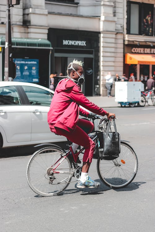 Black man in respirator riding bicycle on busy street · Free Stock Photo