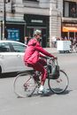 Black man in respirator riding bicycle on busy street