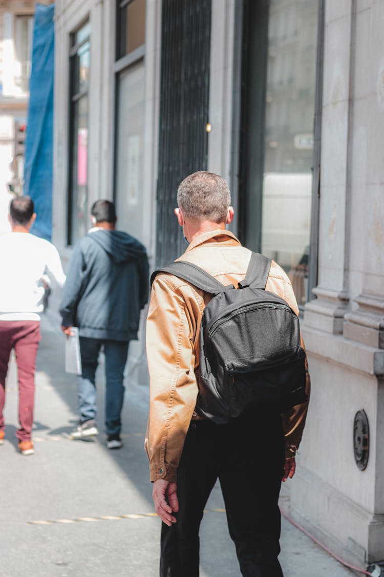 Unrecognizable Man Walking Along Sunny Street Sidewalk