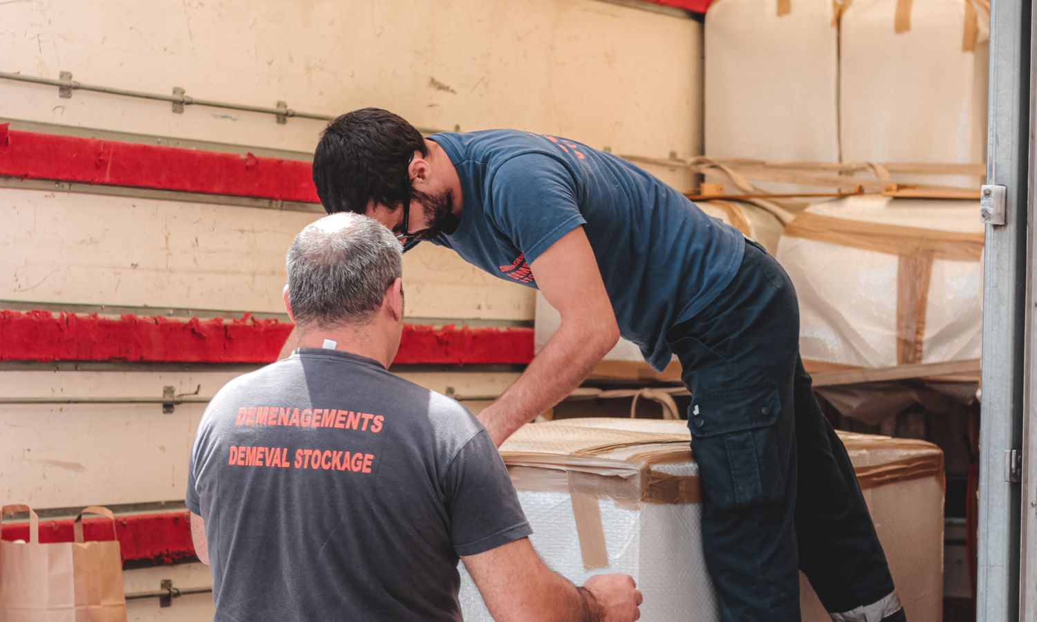 Operarios de mudanza descargando cajas grandes de un camión