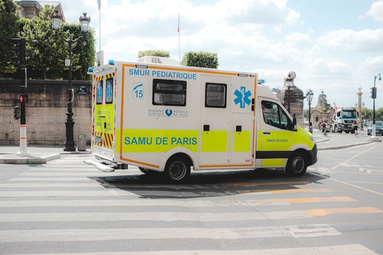 Ambulance Driving Along Road In Sunny City