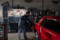 机械师在一个设备齐全的车库里，用火花研磨机修复了一辆老式红色汽车