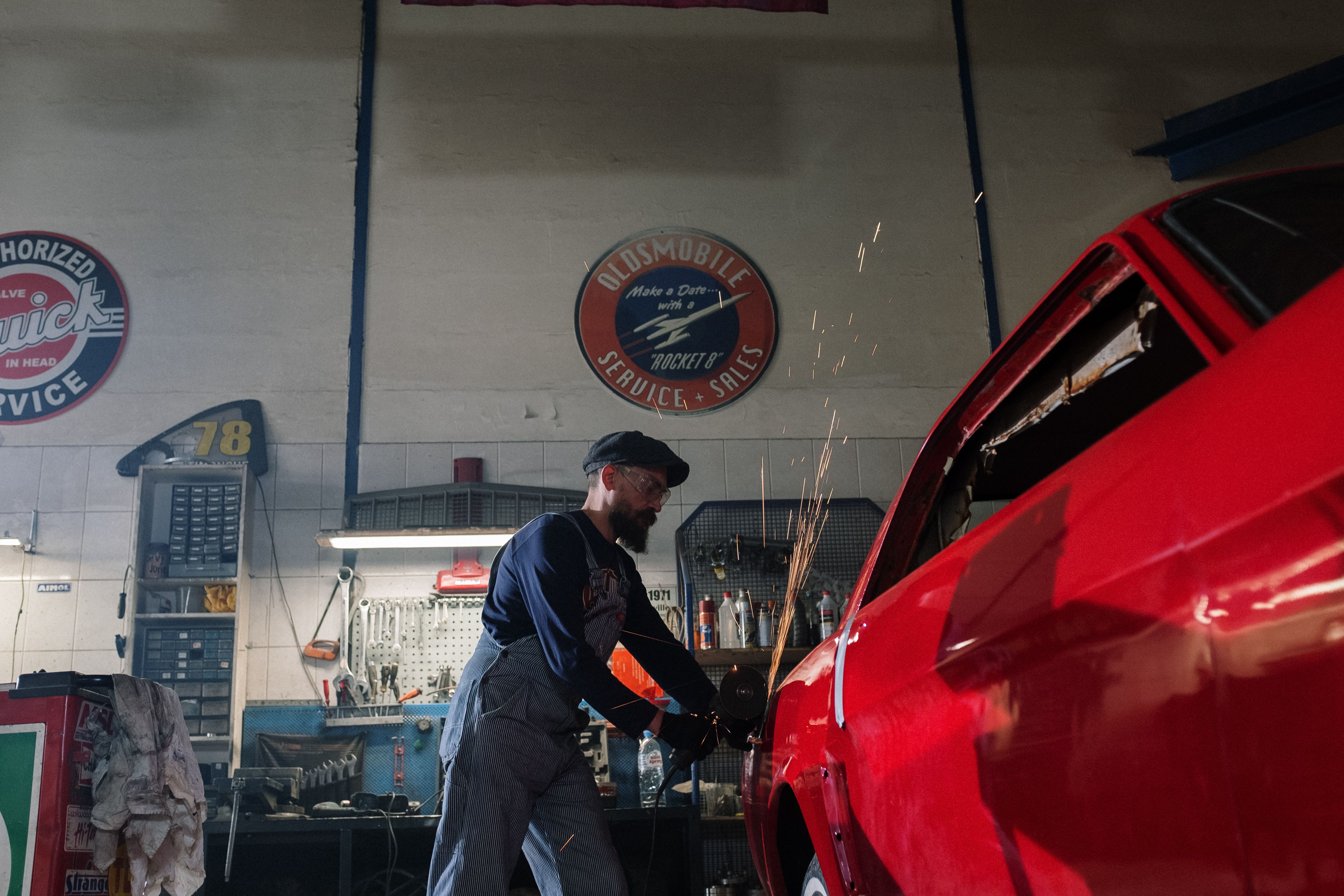 Man in black suit standing beside red car