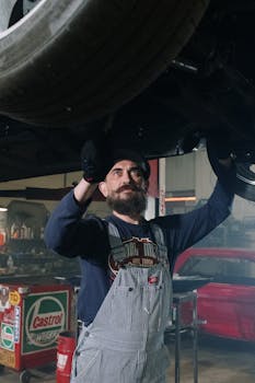 一位留着胡子的专职机械师正在室内修理车辆，展示着汽车专业知识