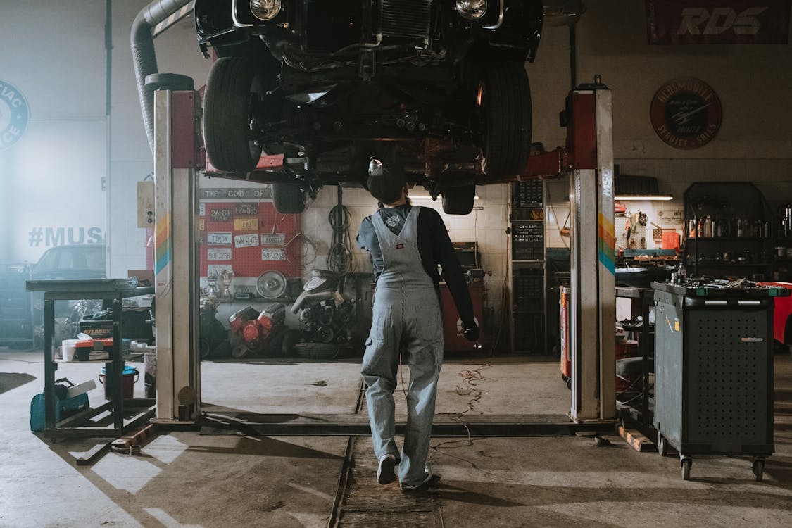 Man in Black T-shirt and Blue Denim Jeans Standing Near Black Car during Nighttime