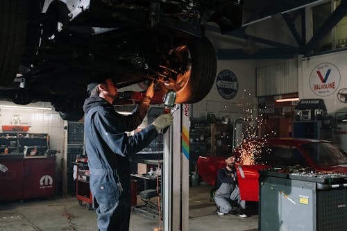 Man in Blue Denim Jacket Holding Brown Metal Pipe