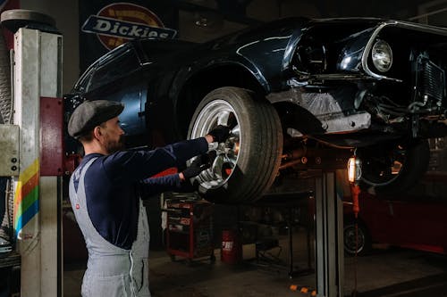 Man in Blue Long Sleeve Shirt and Gray Pants Standing Beside Black Car