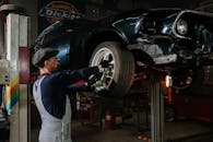 一位专注的机械师在光线昏暗的车库里，正修理汽车车轮，展示着维修技能