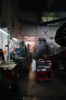 Dimly lit industrial garage filled with car repair tools and machinery, ideal for automotive themes.