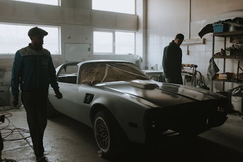 Man in Black Suit Standing Beside Silver Porsche 911