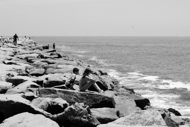 People Sitting On Rocks Near A Body Of Water