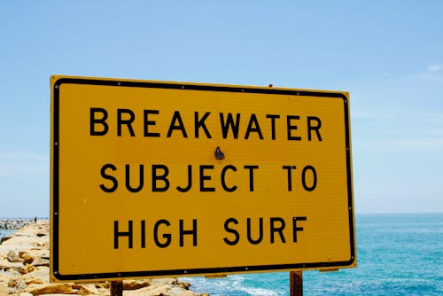 Free Yellow and Black Signage Near the Ocean Stock Photo