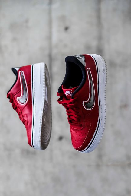 Stylish red sneakers suspended against a concrete background, showing motion.