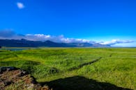 广阔的绿色草地上，群山与蓝天相映，构成夏日里大自然的完美画卷