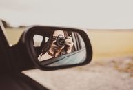 Unrecognizable female photographer taking photos and reflecting in rear window