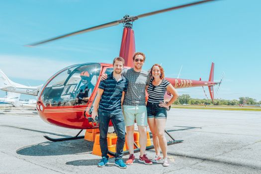 Joyful friends bonding near modern helicopter