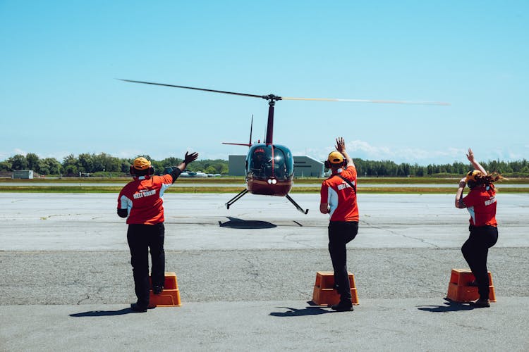 Unrecognizable Airport Workers Directing Helicopter During Arrival