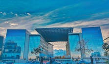 阿拉木图的当代玻璃摩天大楼被群山环绕，映衬在蓝天之下