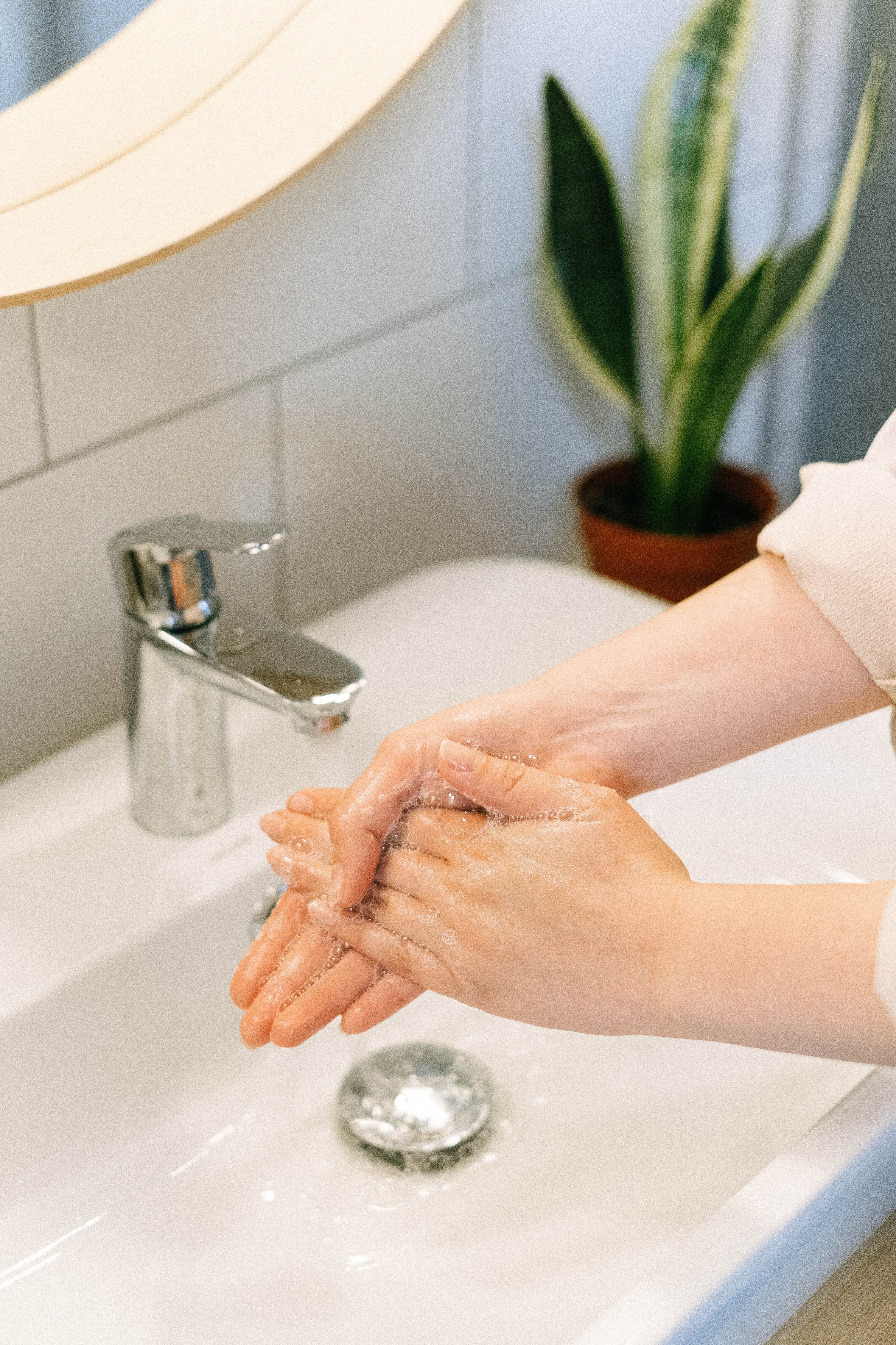 Person washing hands with soap in modern bathroom, emphasizing hygiene and self-care.