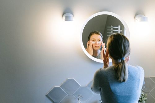 Free A woman applies under eye patches in a modern bathroom, emphasizing self-care. Stock Photo