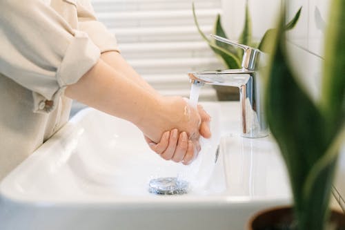 Person Washing Hands on Sink