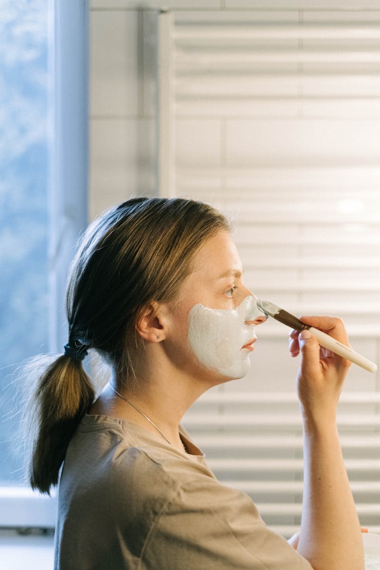 Woman Holding A Makeup Brush Applying Face Cream