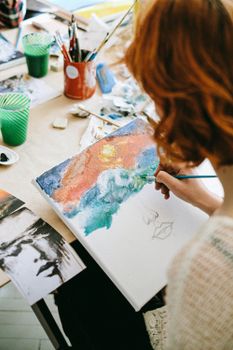一位年轻的女画家在工作室里画了一块彩色画布