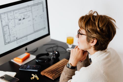 Serious woman reading information on computer monitor while working in modern office