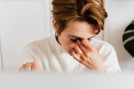 室内，一个女人揉眼睛的特写镜头，传达出压力和乏力