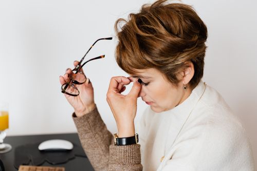 Free Woman feeling stressed and tired at work, holding eyeglasses with eyes closed. Stock Photo